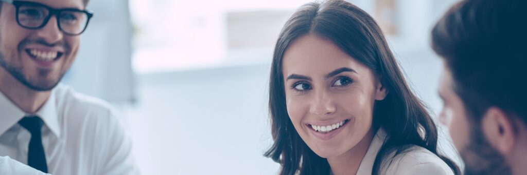 Business handshake. Close up of two young man shaking hands with smile while sitting at office with their beautiful coworker